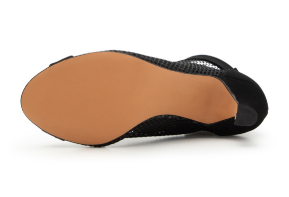 Die Sohle eines schwarzen Absatzschuhs mit glattem hellbraunem Boden, von unten gesehen.